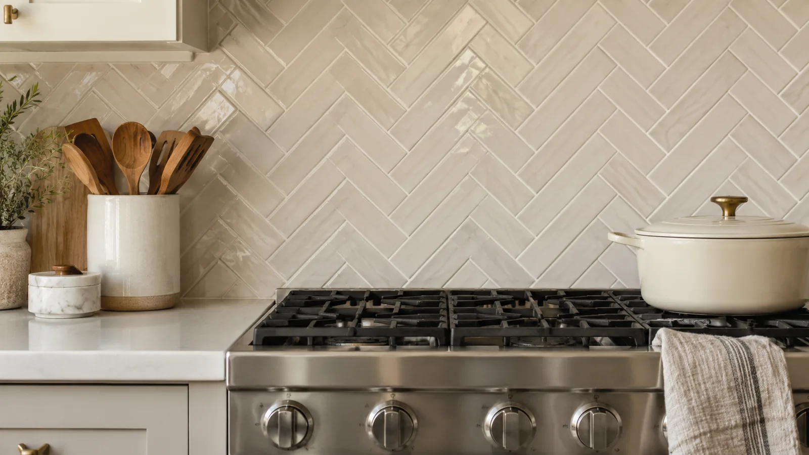 Creamy white 2x8 tiles in a herringbone backsplash behind a stainless range