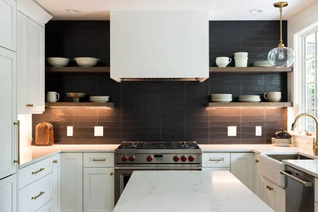 Luxurious kitchen with matte black subway tile backsplash, white cabinets, and brass hardware