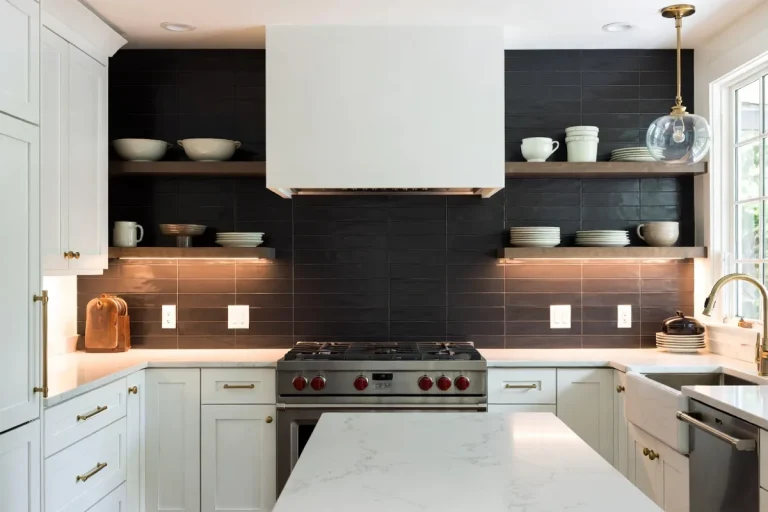 Luxurious kitchen with matte black subway tile backsplash, white cabinets, and brass hardware