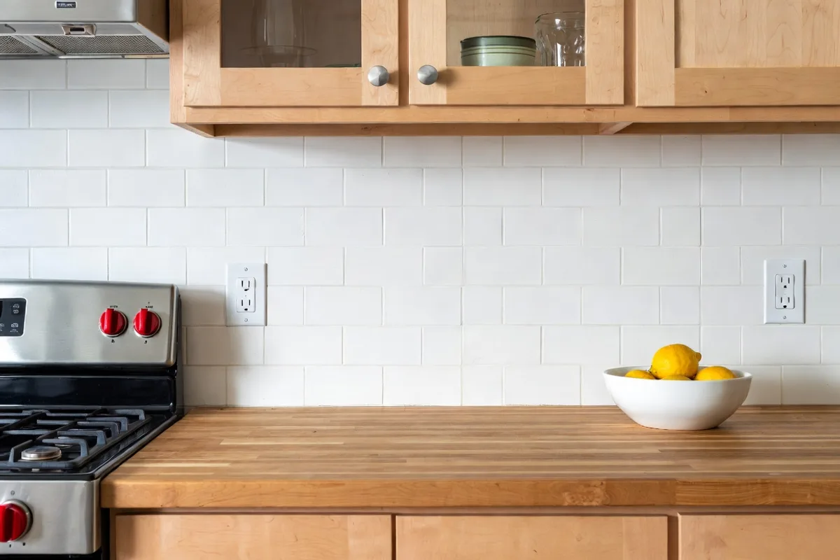 DIY painted faux tile kitchen backsplash with painter's tape grid effect and wood cabinets