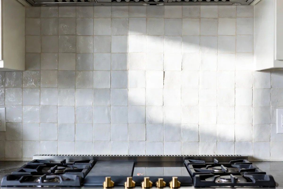 White Zellige tile kitchen backsplash with handmade texture catching natural light behind a range