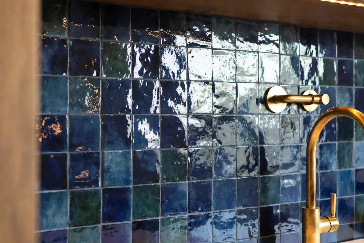 Deep navy Zellige tile kitchen backsplash with handmade texture and brass fixtures