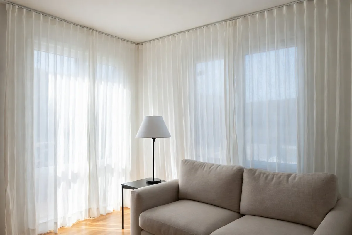 Curtains hung high and wide near ceiling in small living room to make windows appear larger and ceilings taller