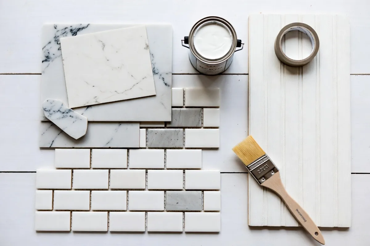 Collection of budget kitchen backsplash materials including peel-and-stick tiles, paint, and beadboard samples
