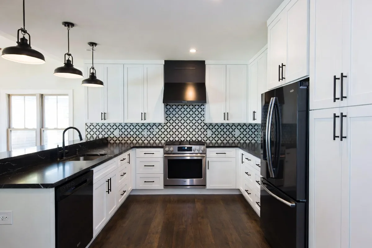 Bold graphic black and white cement tile backsplash with white cabinets