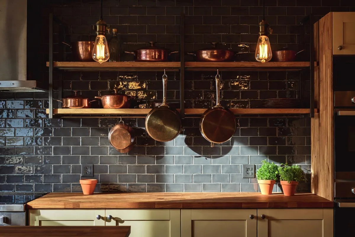 Textured charcoal brick tile kitchen backsplash with warm wood shelving and copper accents